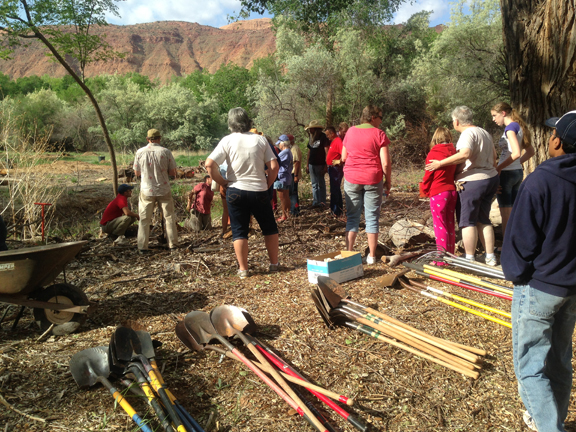 People standing around piles of shovels